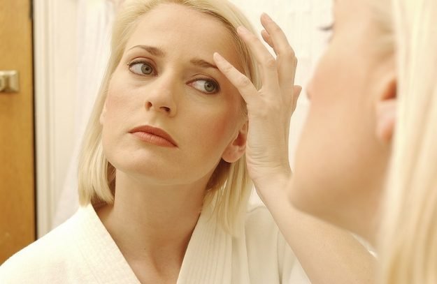 woman checking aging signs in mirror