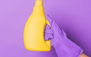 crop person with yellow bottle with detergent