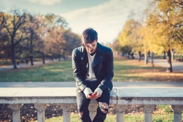 Guy sitting on a fence and missing his ex girlfriend