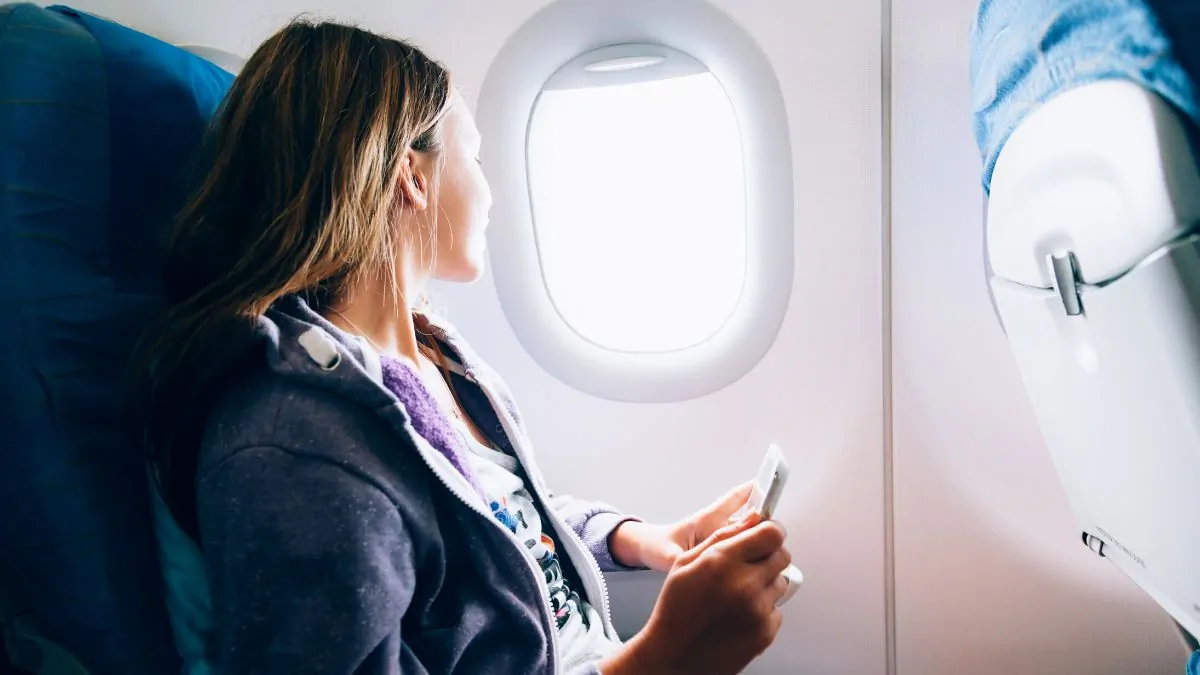 Woman sitting in an airplane and listening to music online
