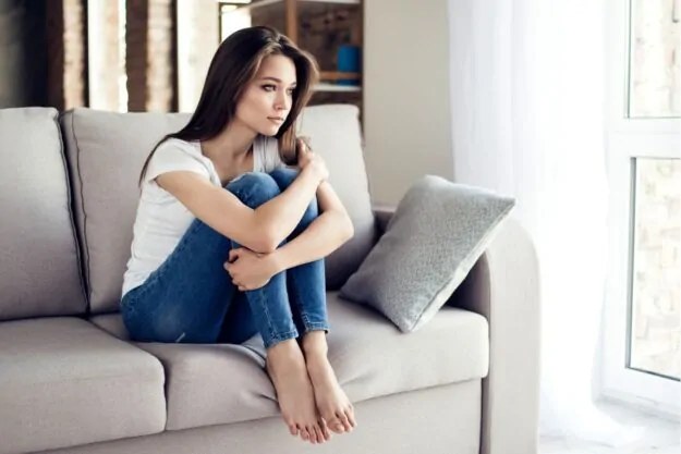 Thinking sad woman sitting on the couch